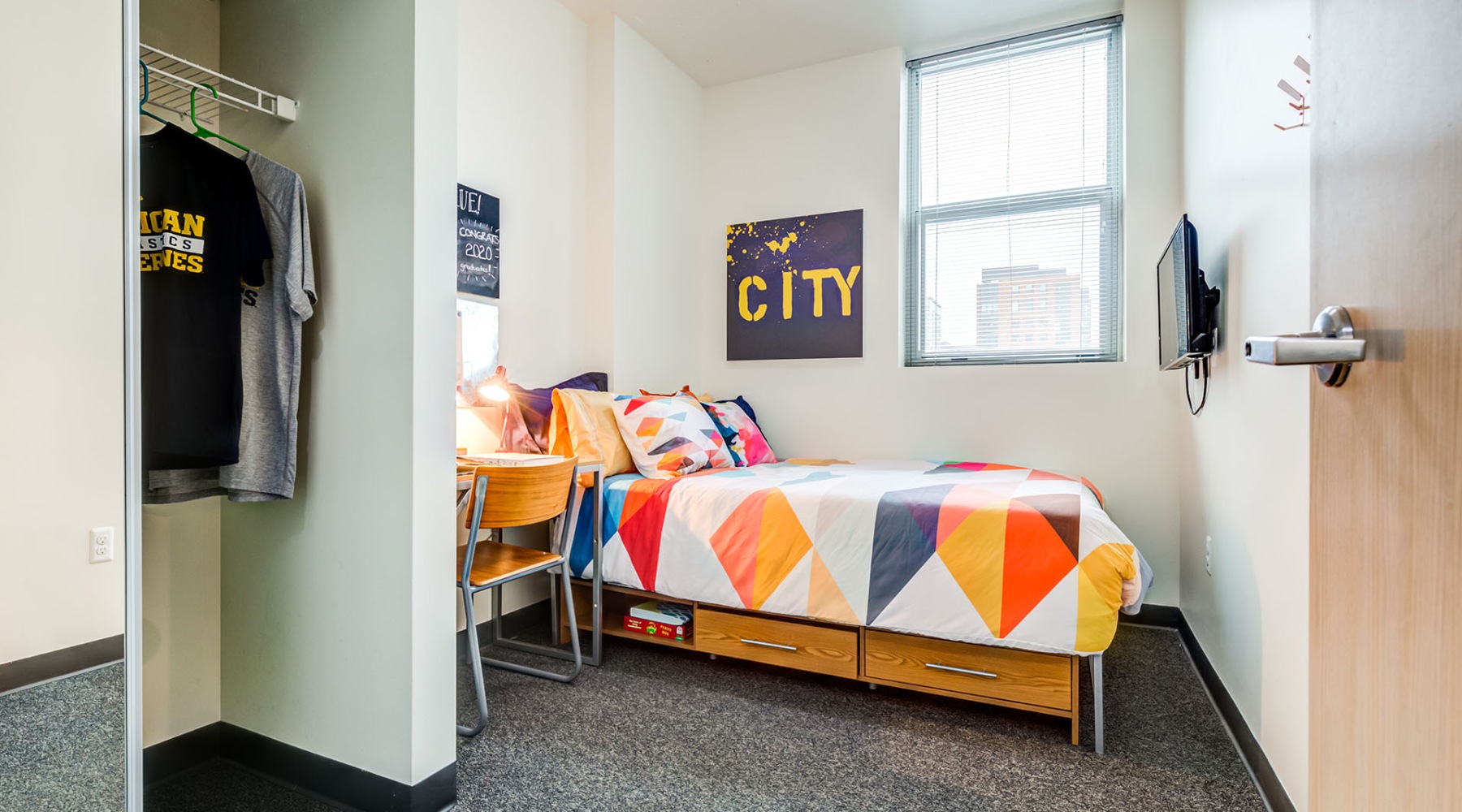 bedroom with colorful bedspread window and closet